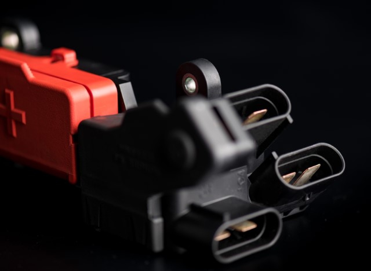 Close-up of the red battery-positive pre-fuse connector and three mating ports